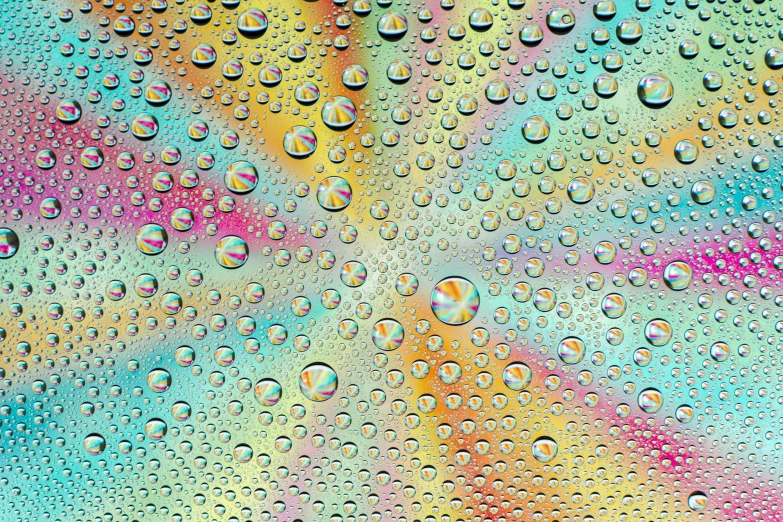 close up of droplets on glass with colorful background