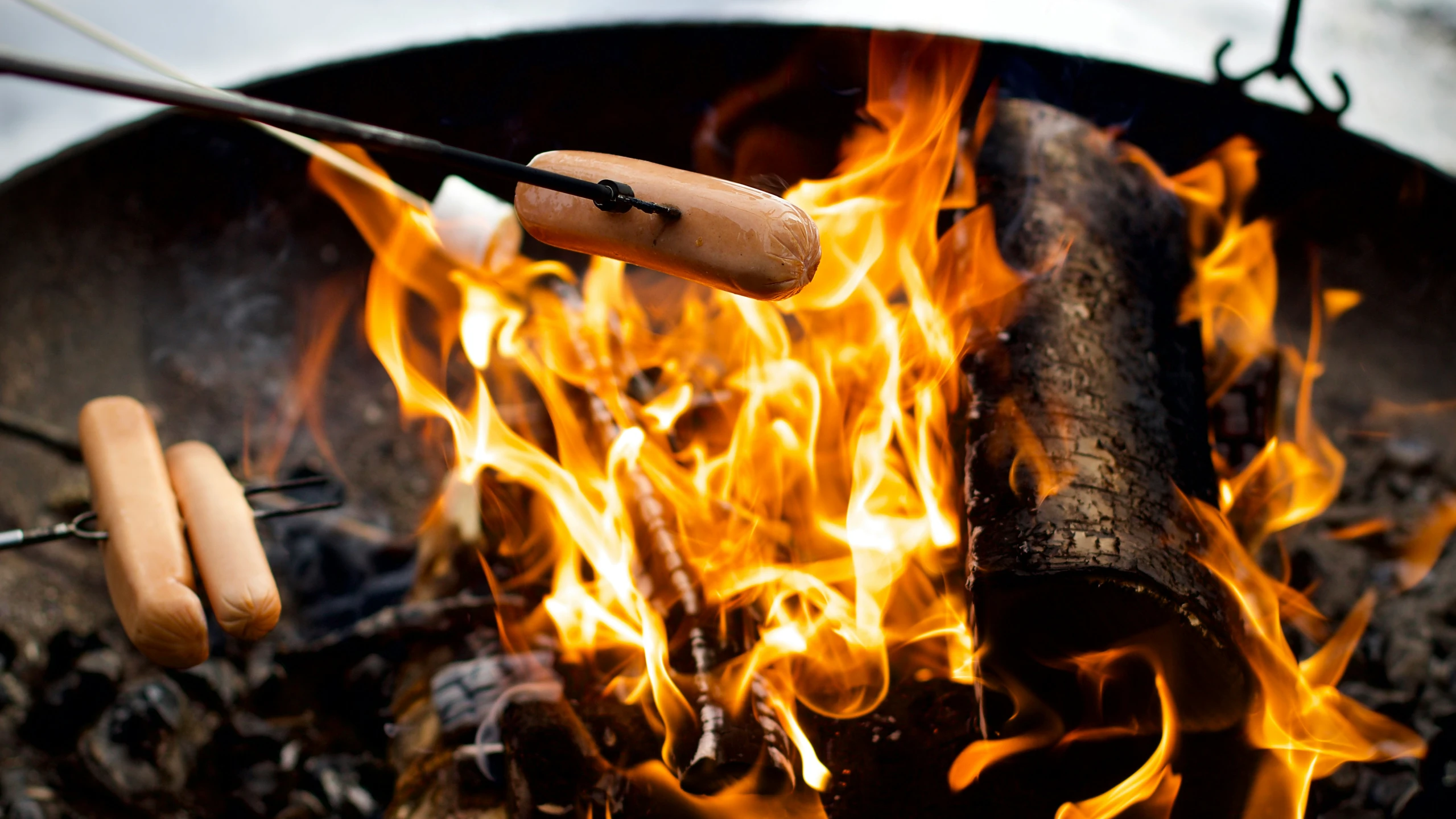  dogs are cooking over a grill with flames