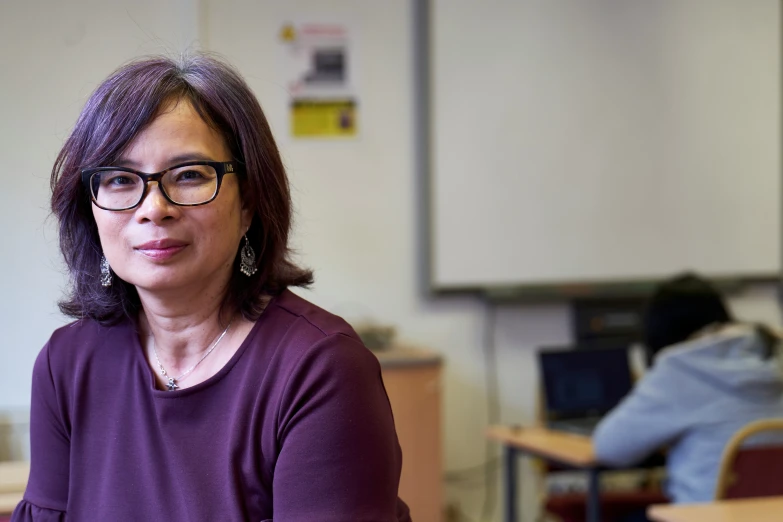 a woman with glasses is sitting in front of a desk