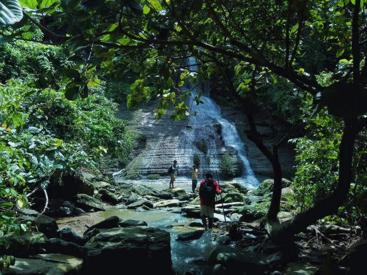 two people standing in front of a waterfall