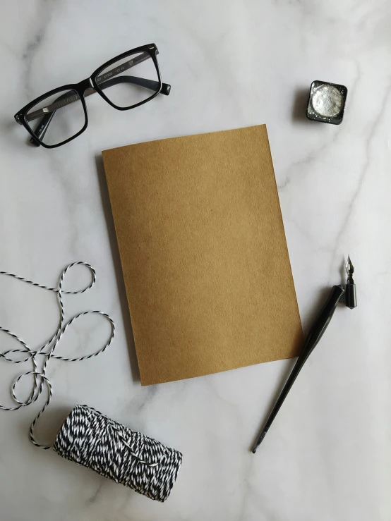 notebook on white table with silver accessories