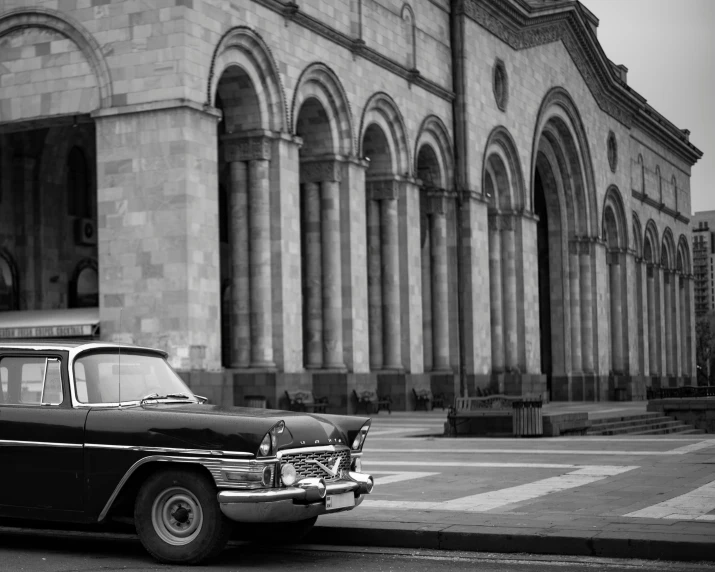 a classic car parked outside a large building