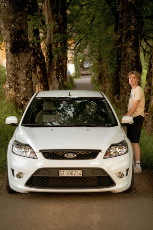 a  leans on the front of a white car