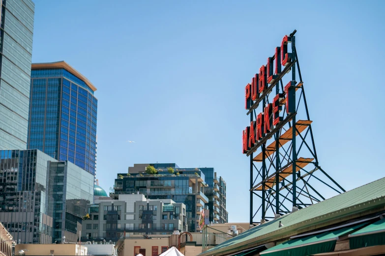 a neon sign is above the rooftops on a clear day