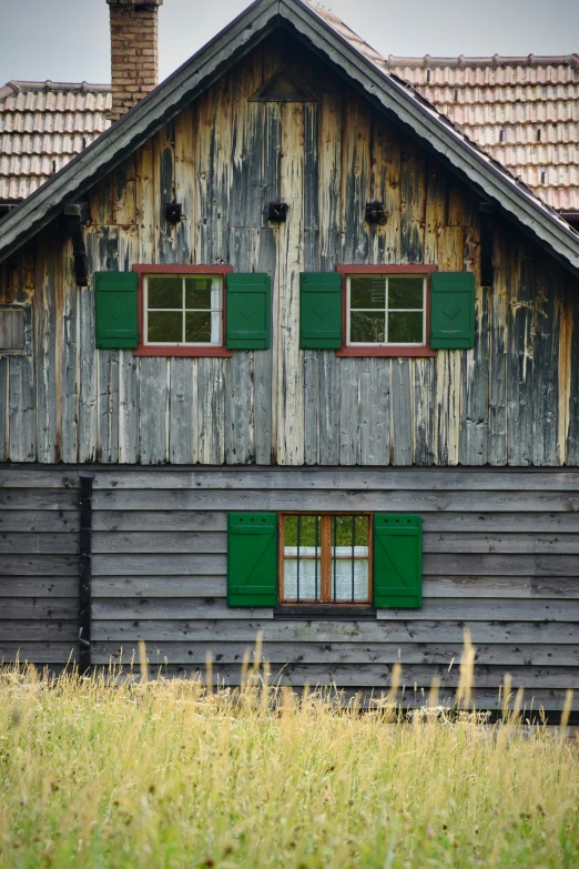 a house made out of wood, with wooden shutters and green doors