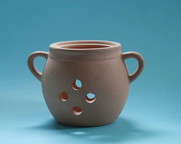 there is a ceramic vase with holes in it