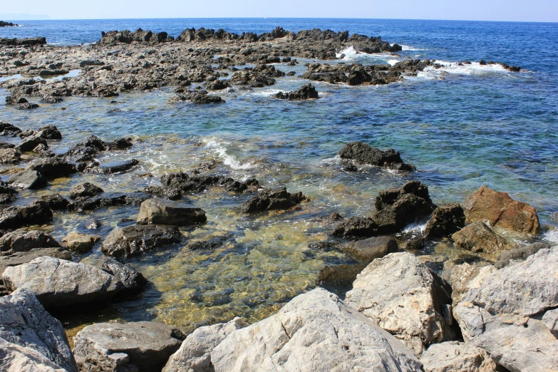 rocks covered in green algae and water against the blue sky