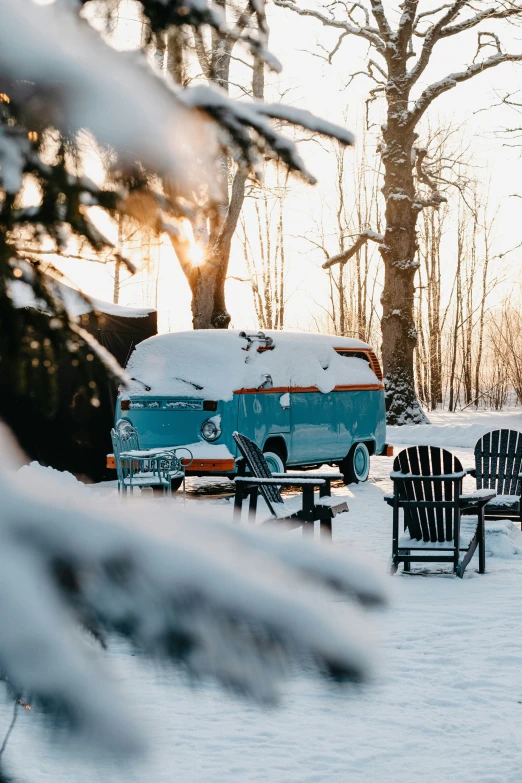 a camper trailer parked in the snow next to a couple of chairs