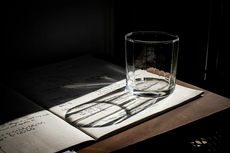 a book with a glass on it in the sunlight