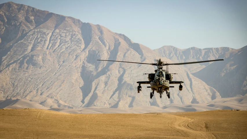 the helicopter flies over the desert and some mountains