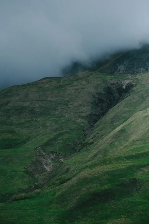 an up - rolling mountain with the clouds above