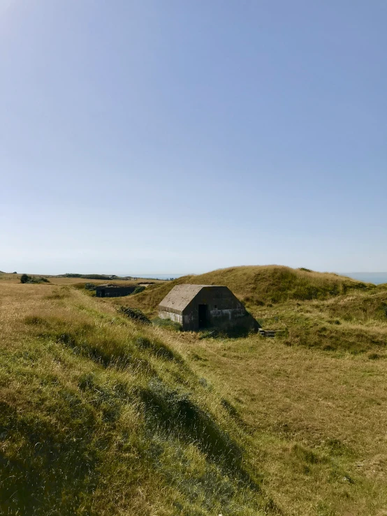 a small hut on top of a green hill