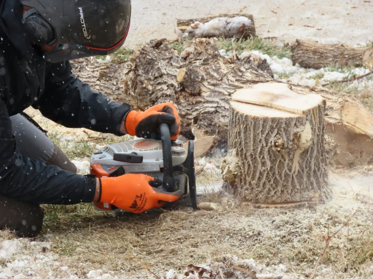 a man with an orange safety jacket holding a chainsaw