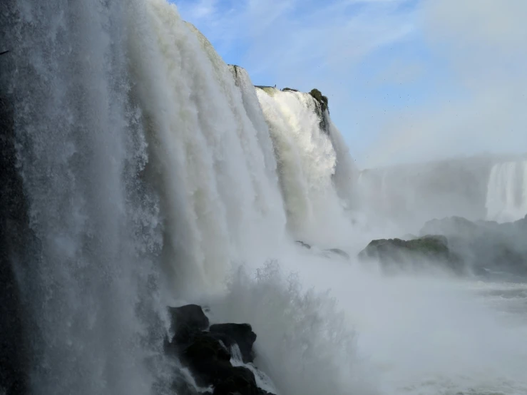 an enormous waterfall on a river with people in the distance