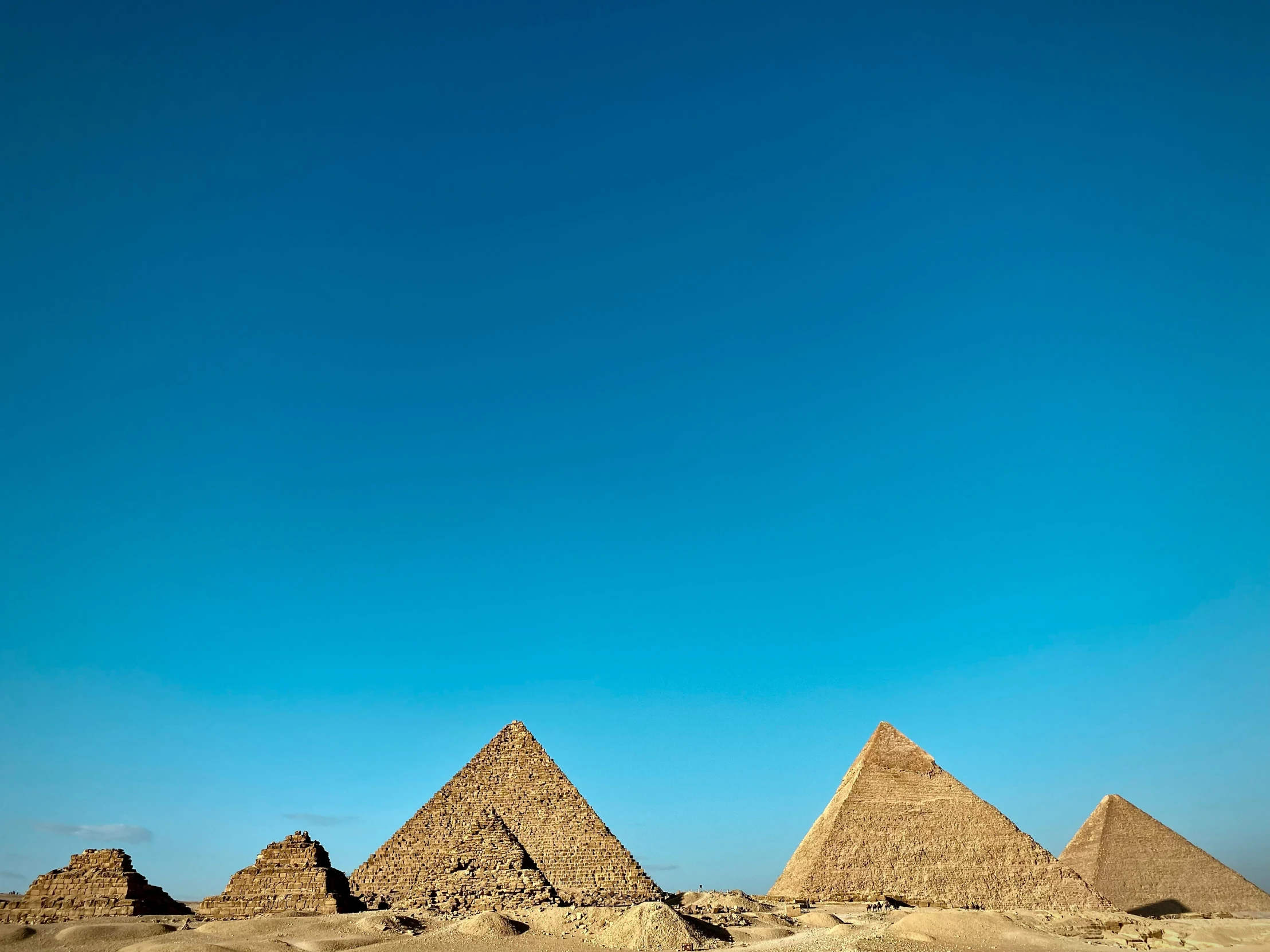 three pyramids sitting side by side against a bright blue sky