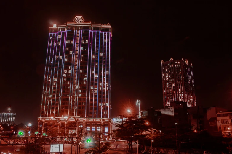 a very tall building with bright lights near a busy street