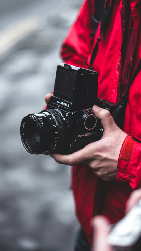 a person holding a camera while standing on the sidewalk