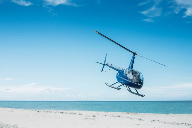 a helicopter is flying over a sandy beach