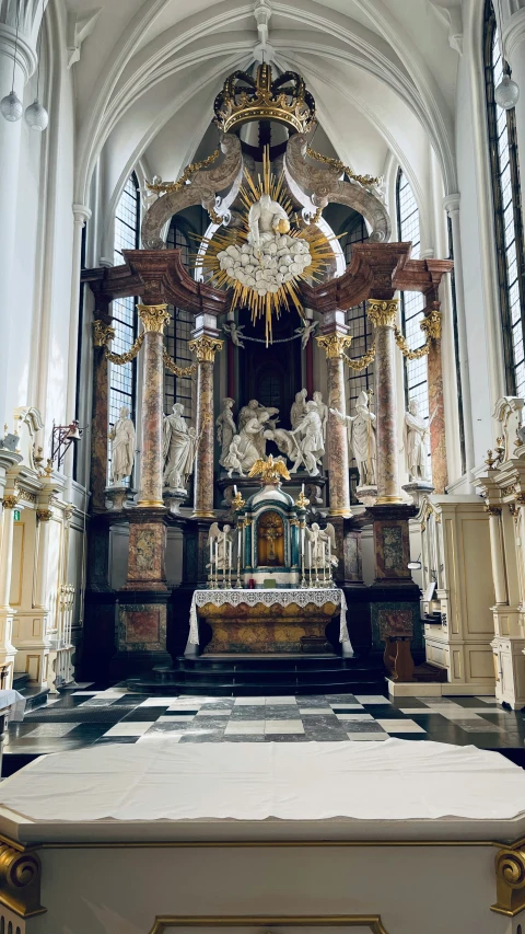 large statue of saint in gold and ornate interior with cross above