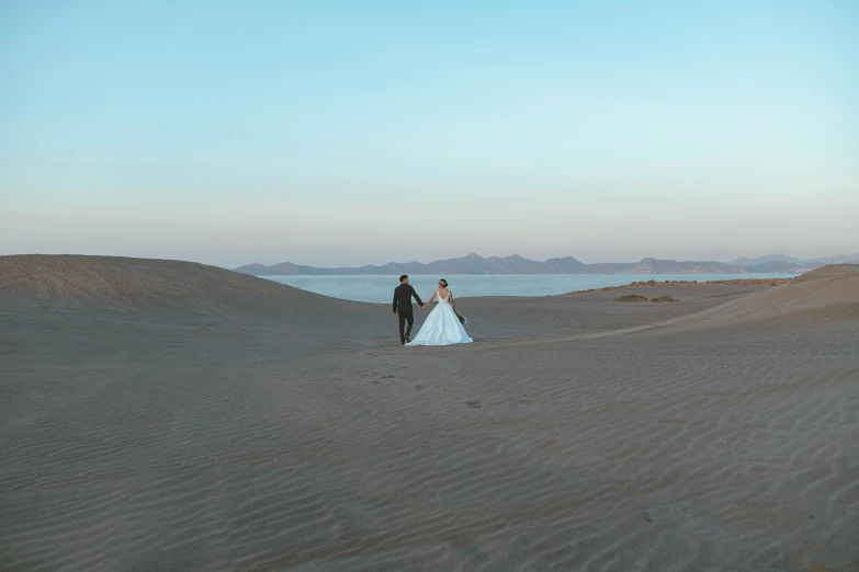 a couple standing on top of a sand covered hill