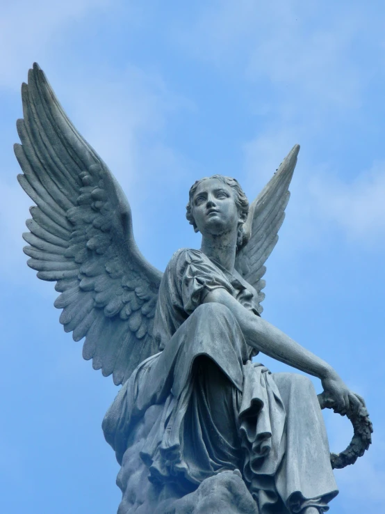 a statue of an angel sits on top of the base of a tall tower