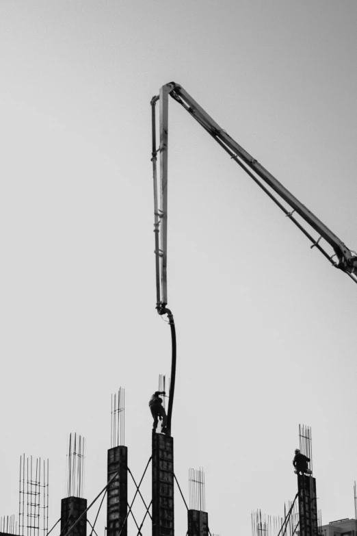 a black and white image of a construction site with the crane working