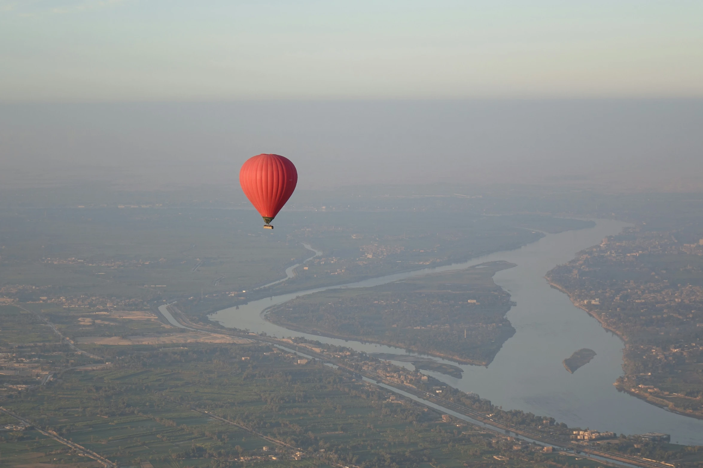 a  air balloon floats above a river and a town