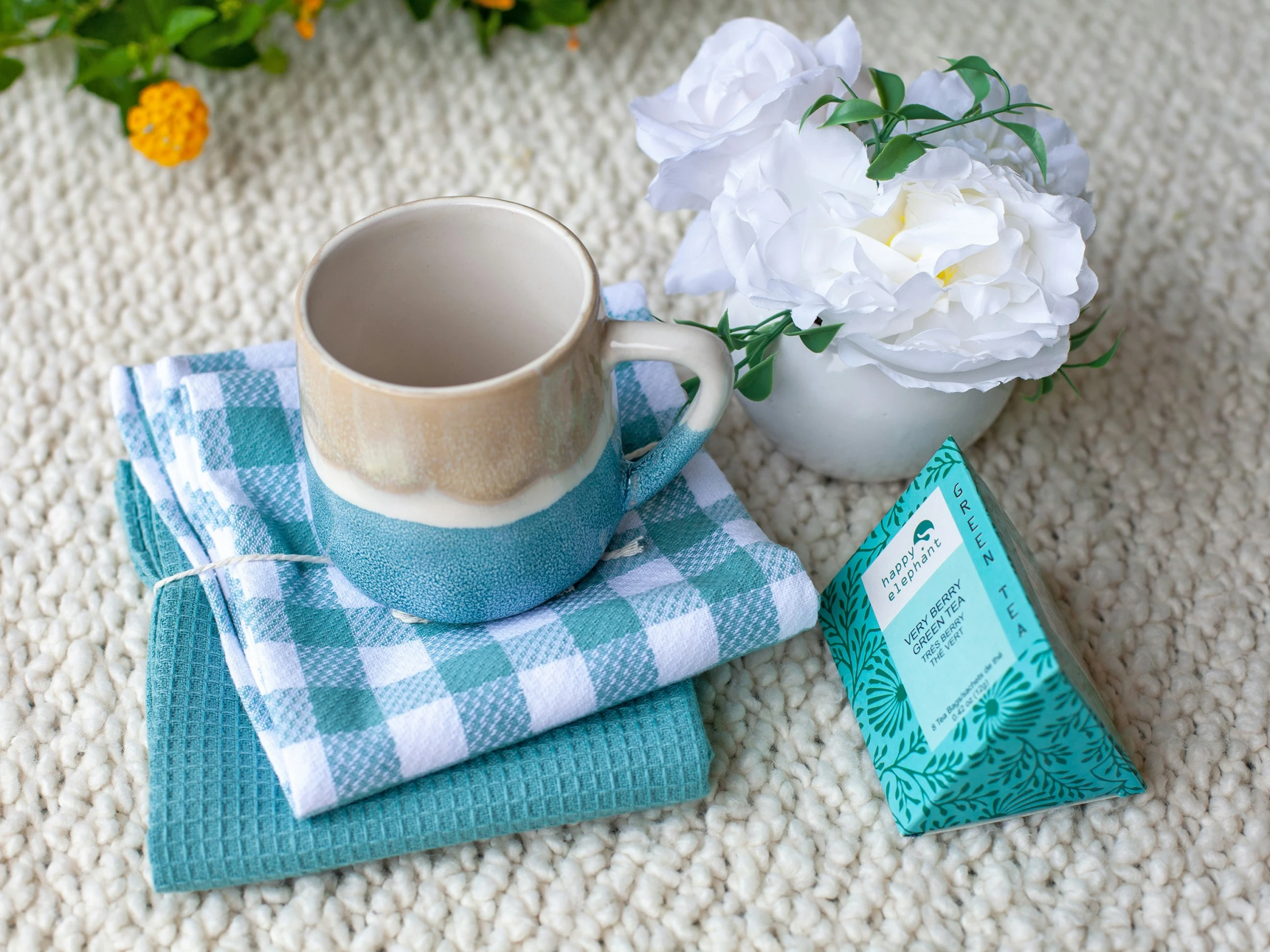 a cup and napkin sitting next to a container of white flowers