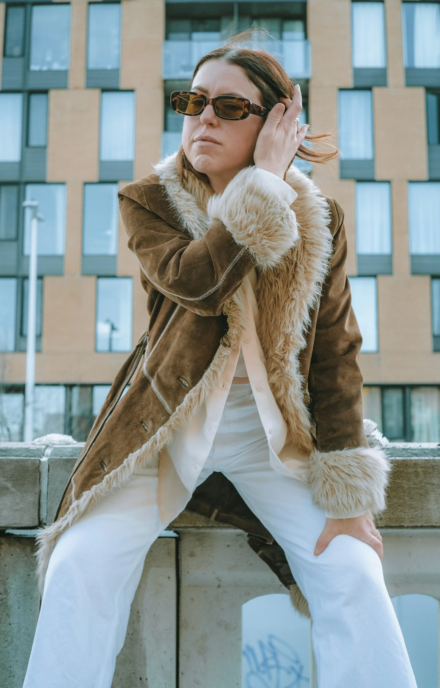 a woman with sunglasses sitting on top of a cement wall