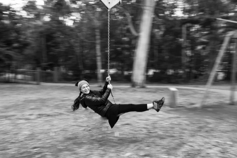 woman in black jacket swinging from tree swing