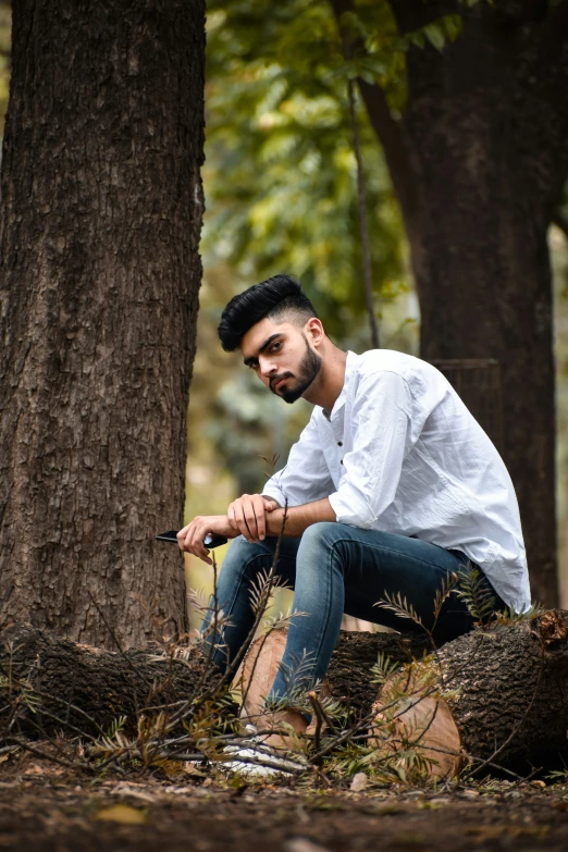 a man sitting on a log in the woods