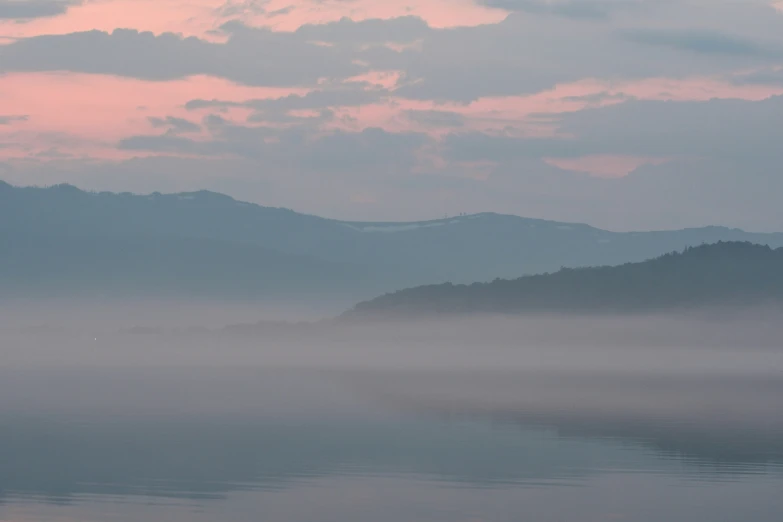 a boat floating on top of a lake next to mountains