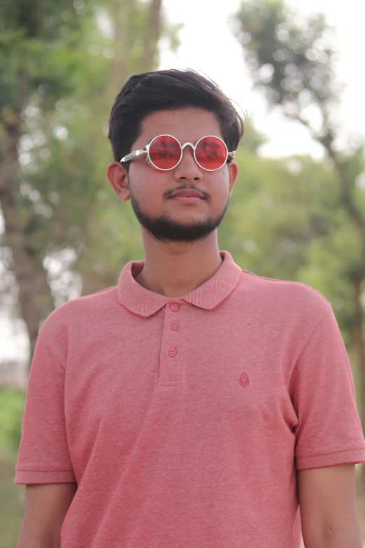 a young man wearing sunglasses stares off into the distance