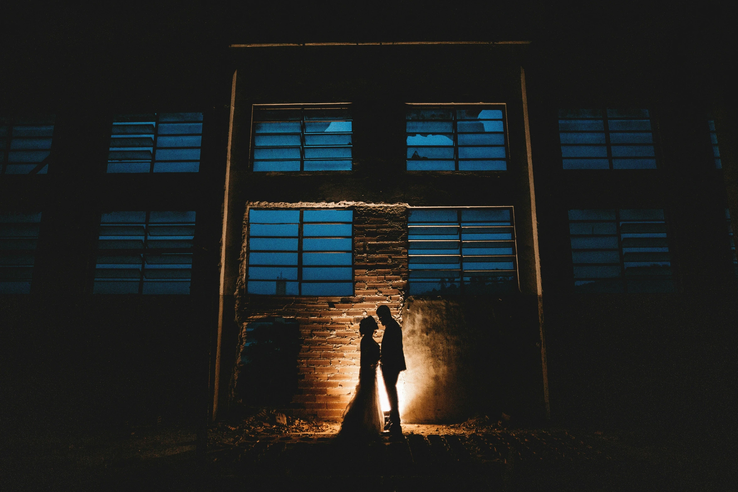 two people standing in front of the window of an open building