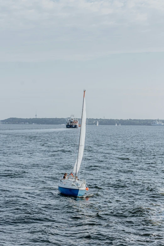 a sailboat in the middle of a lake with other boats in the background