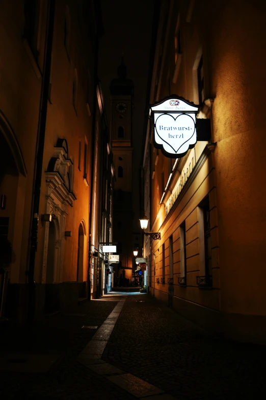 an alleyway in an old town with a lit up sign