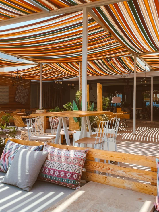 an outdoor restaurant covered by multi - colored awnings