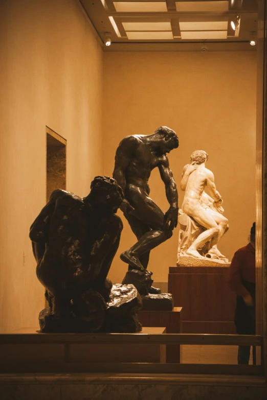 three statues in an art museum setting one being seated and the other standing