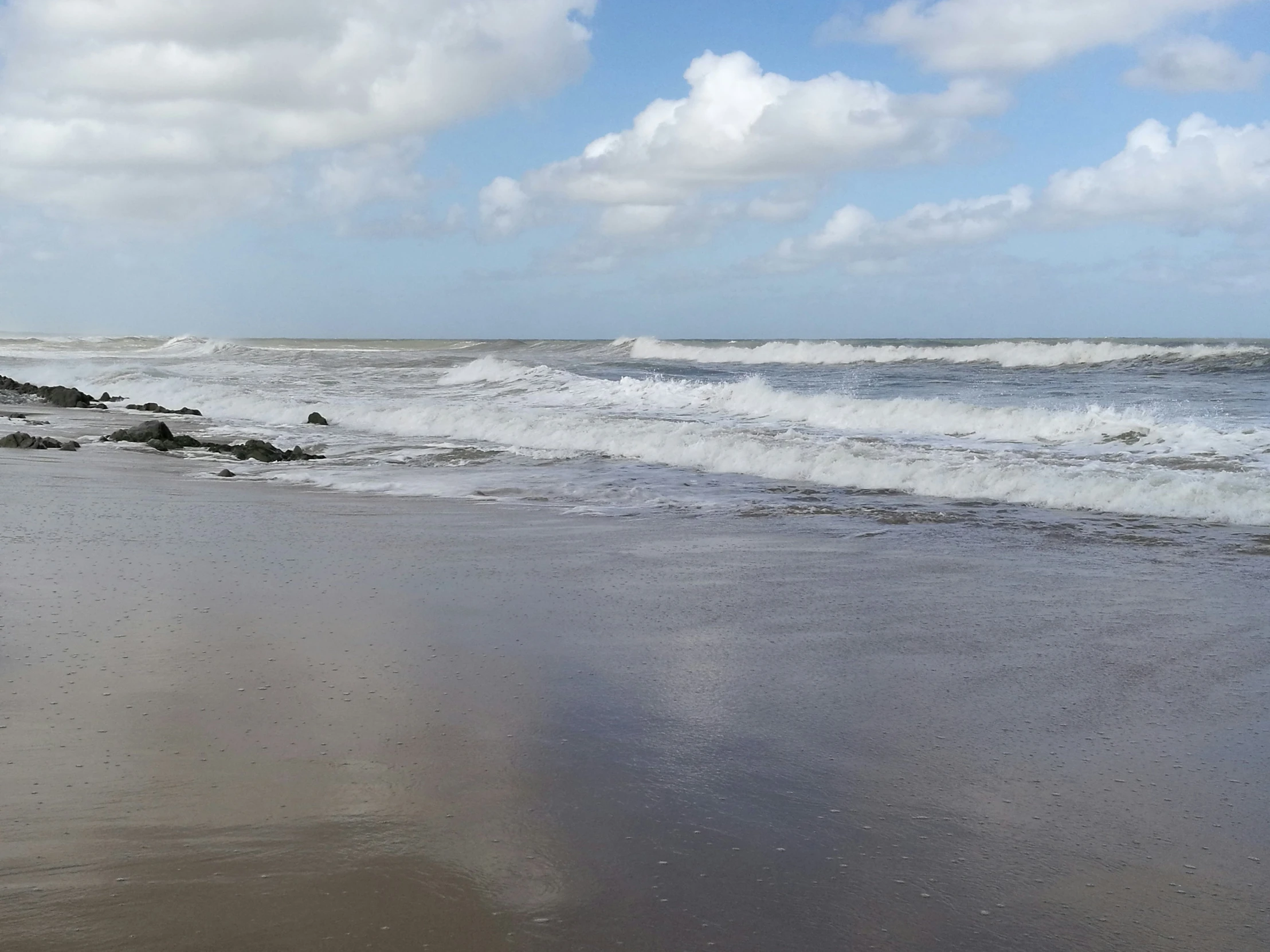 a beach area with the ocean and rocks in the foreground