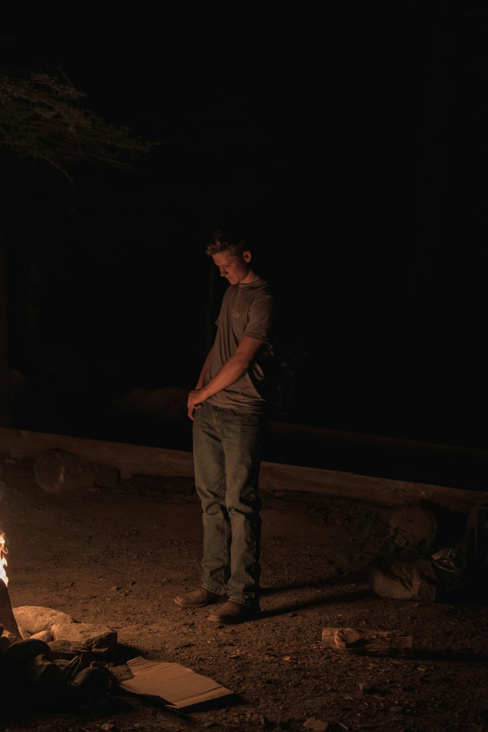 a man standing next to a fire in the dark