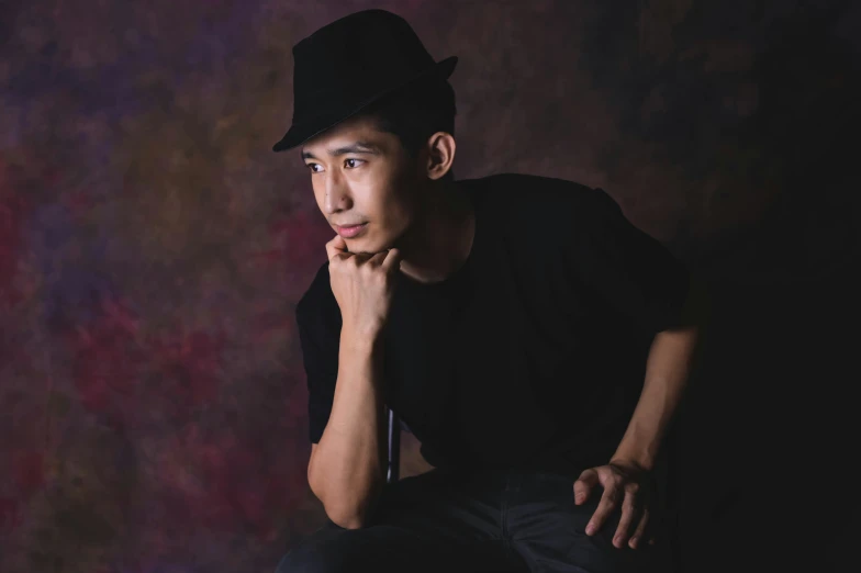 a young man poses for a picture wearing a black hat