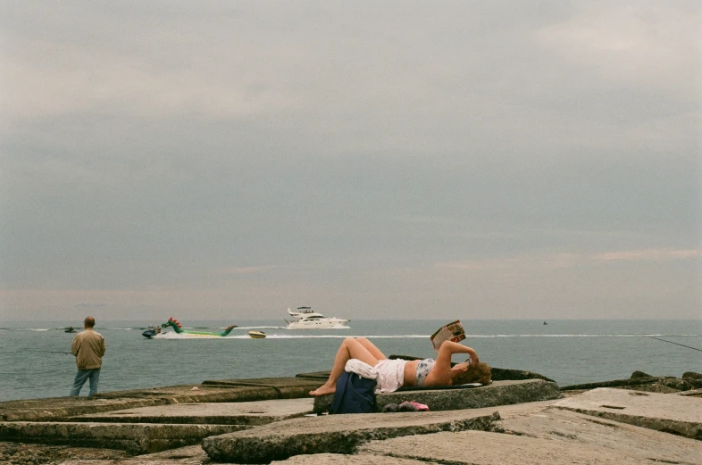 a man laying on rocks next to the ocean