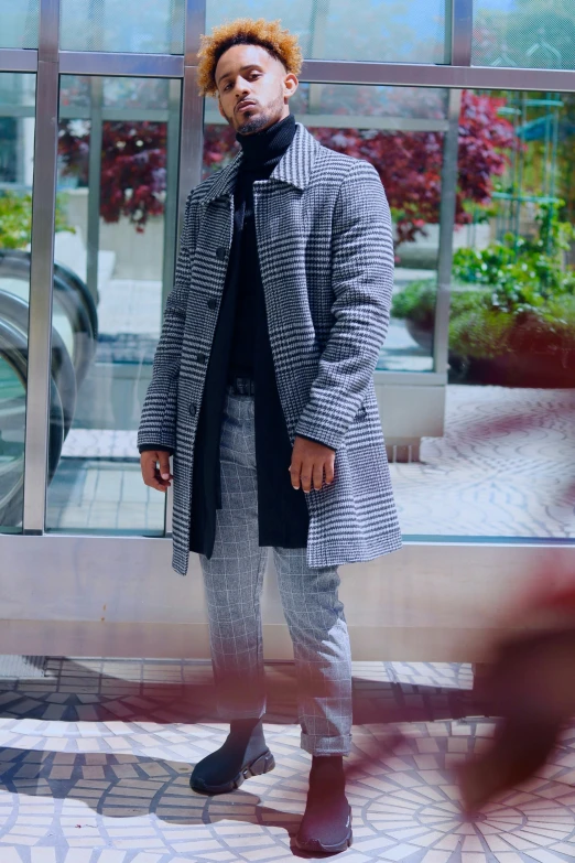 a man with an afro is standing near a building