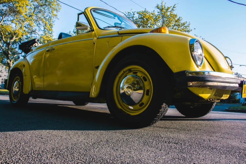 an old yellow car parked on the side of the street