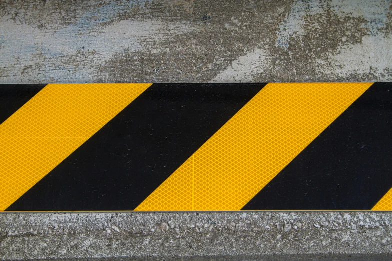 a yellow and black street sign is placed on the cement
