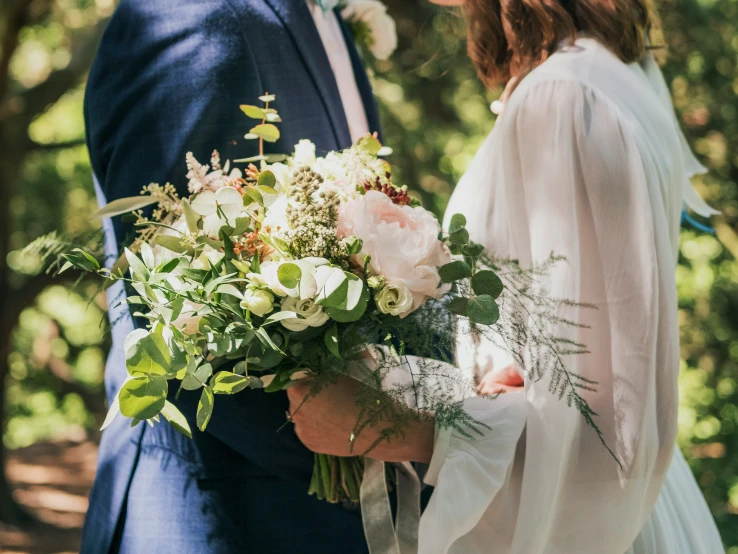 a beautiful young couple stand together under a forest filled with trees