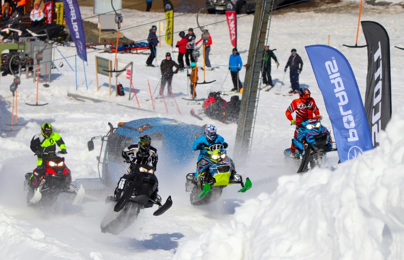 a group of snowmobiles race through the snow