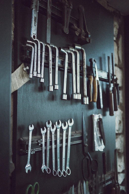 a bunch of tools hang from hooks on the wall