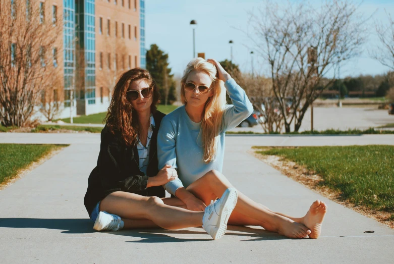 two women sitting in the street one is holding her head