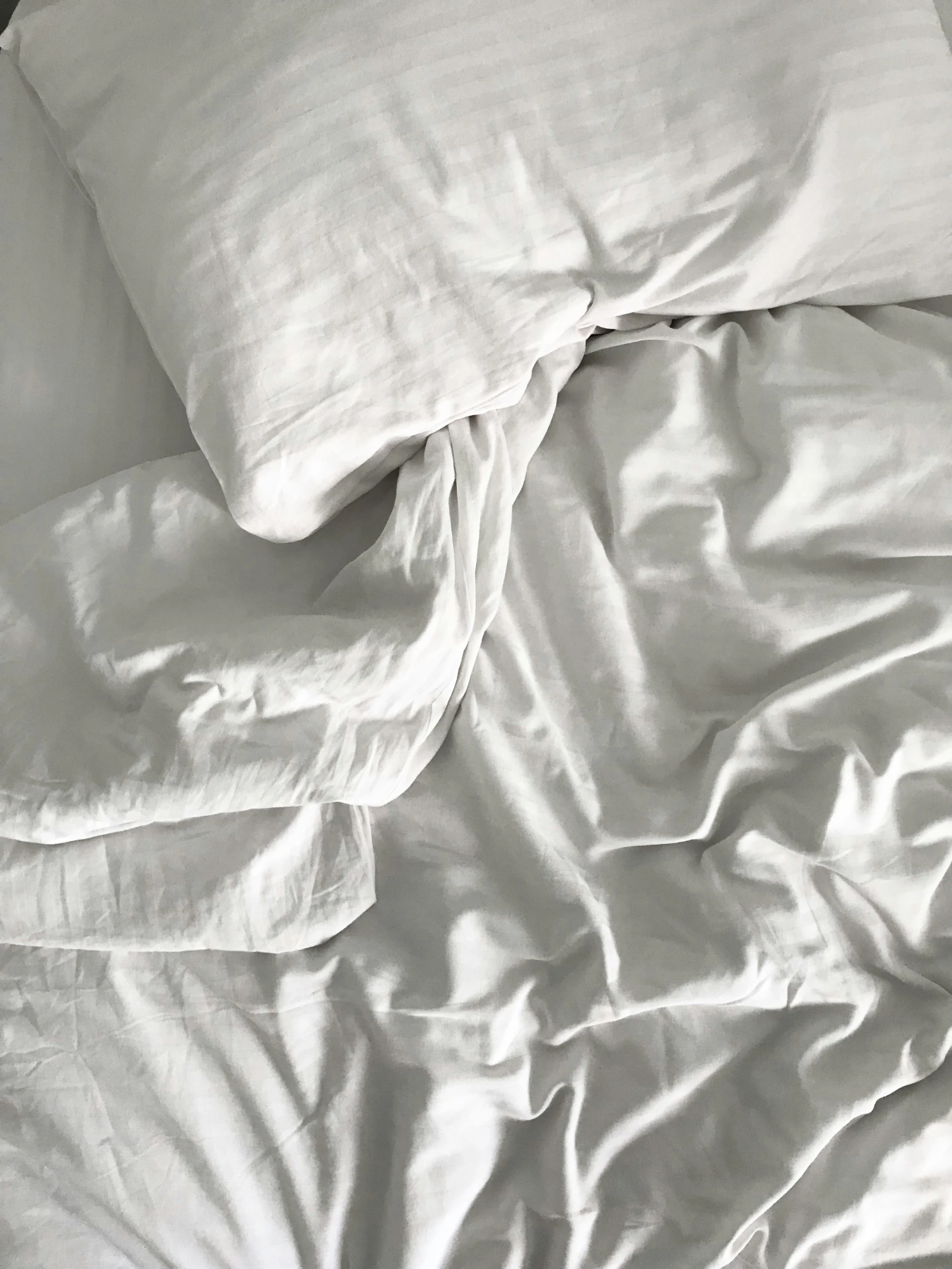 the bed is covered with white sheets and pillows